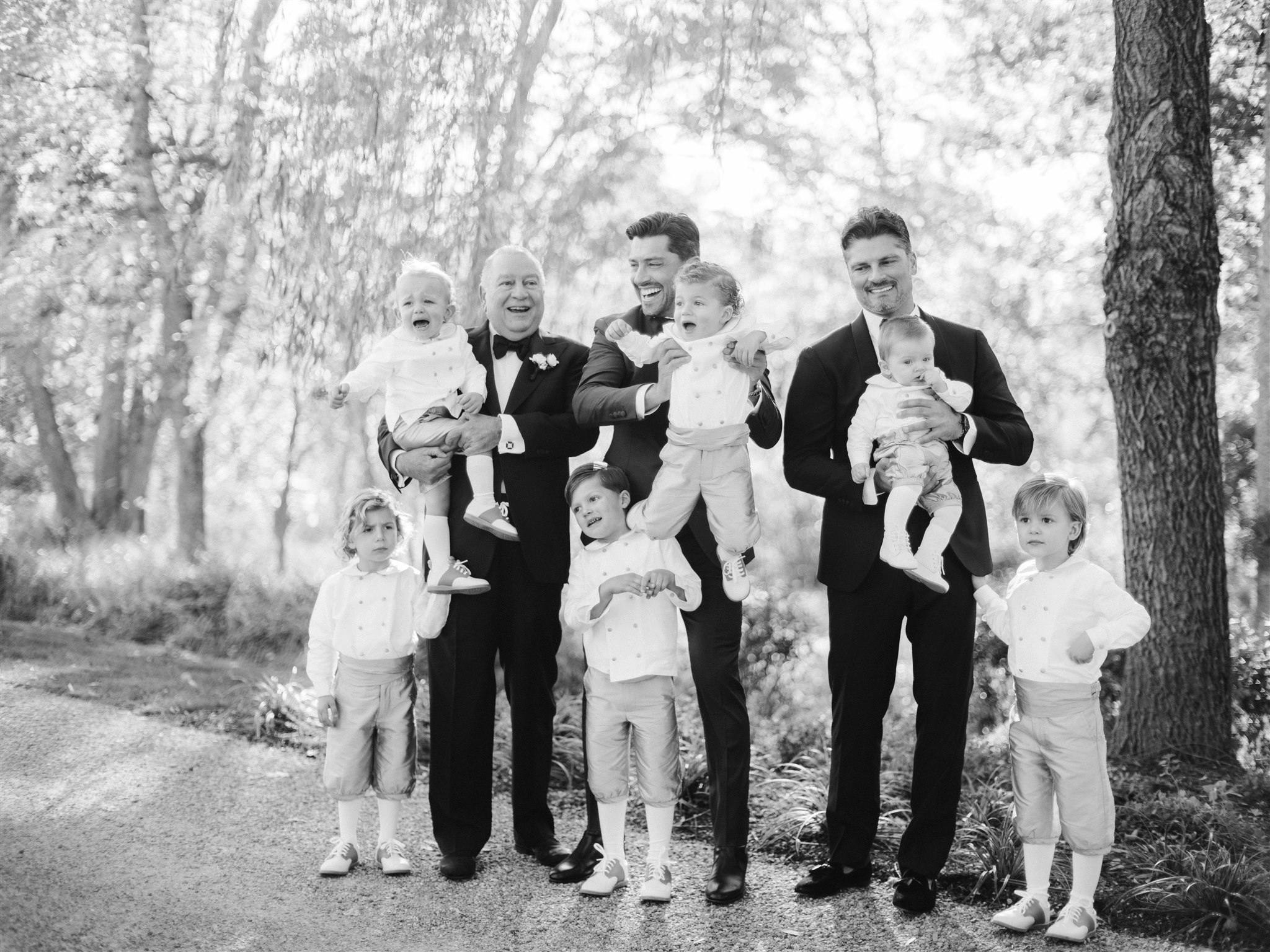 Black and white photo of six kids and three men all smiling and matching | PartySlate