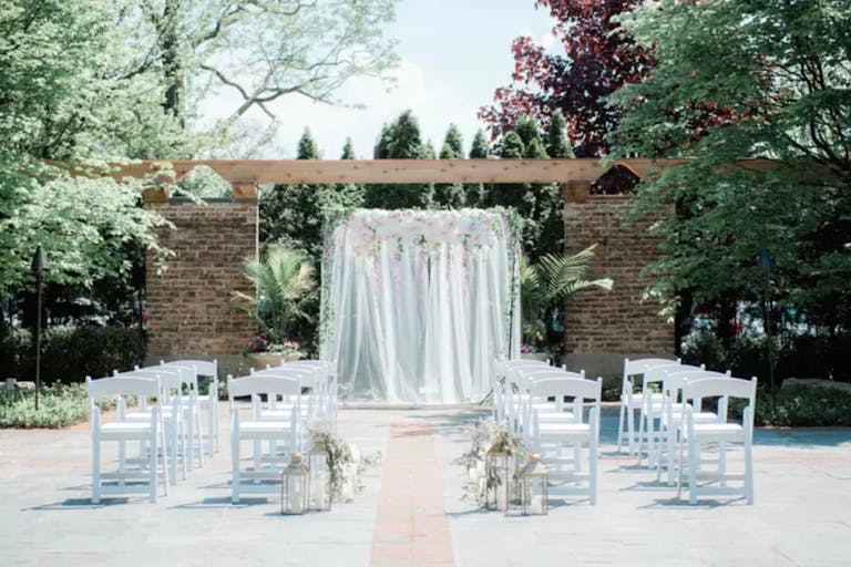 Outdoor all-white wedding ceremony in The Garden Room at Community House Winnetka | PartySlate