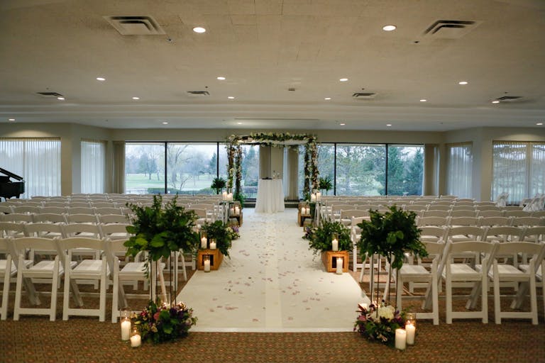 Indoor candlelit ceremony embellished with vines and and white flowers at Ravinia Green Country Club in Riverwoods, IL | PartySlate