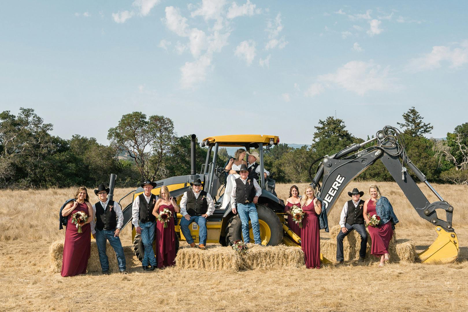 Bridal party in front of tractor machine on farm l PartySlate