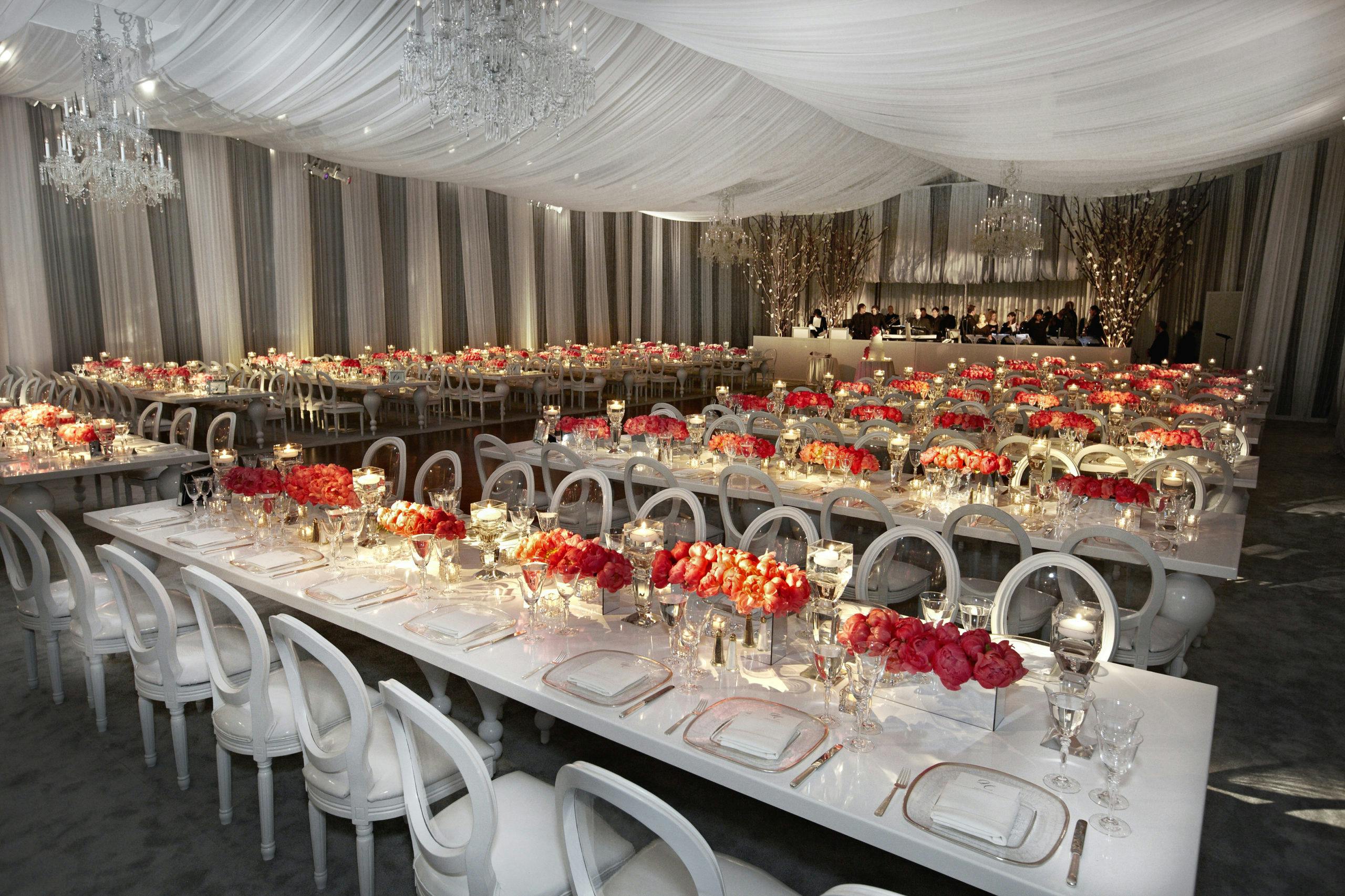 Tented reception venue with orange floral centerpieces l PartySlate