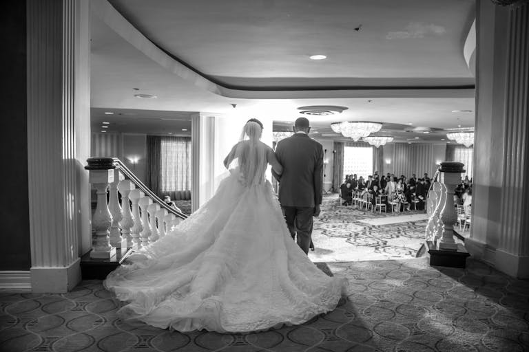 Bride and groom descend iconic stairway to Grand Ballroom at Hilton Orrington Hotel Evanston | PartySlate