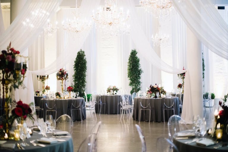 all-white sheer drapery framing wedding aisle flanked by topiaries at Chez in Chicago | PartySlate