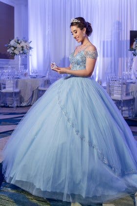 Quinceañera in Blue Cinderella Ballo Gown Stares at Glass Slipper in Purple-Uplit Ballroom Reception Planned by The Soirée Co. Wedding and Event Planning | PartySlate