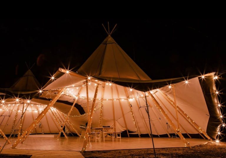 Nighttime wedding reception in Nordic tipi at At the Shire in Piney Woods | PartySlate
