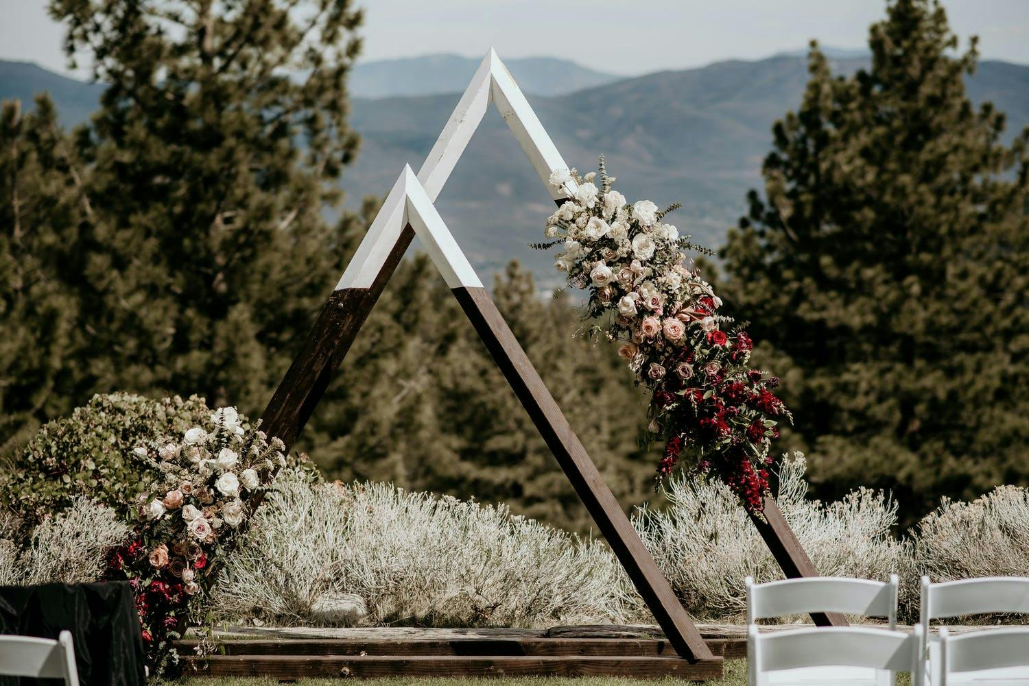 Twin triangular arches decorated with ombré blooms at wedding ceremony in mountains | PartySlate