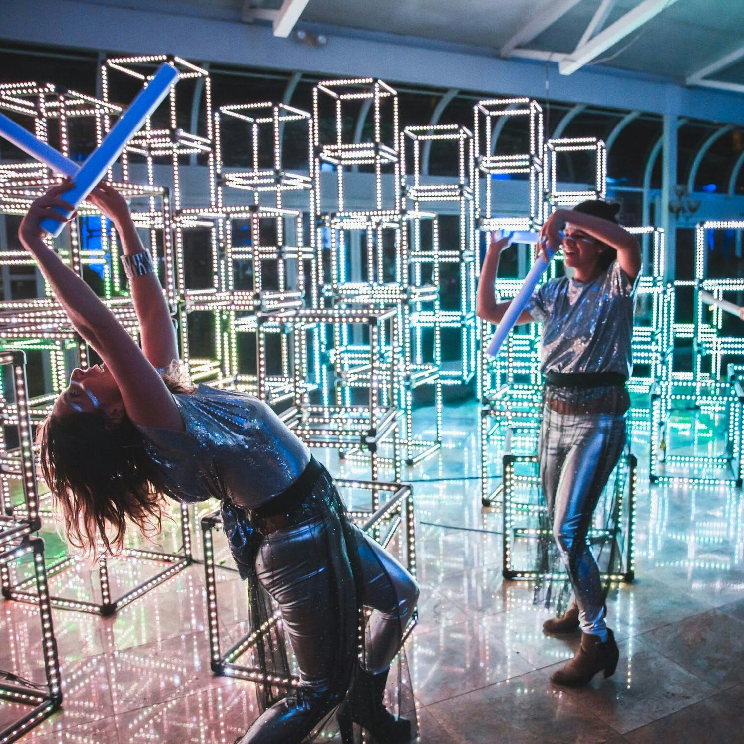 Pillars of cubes stacked together are in the background of 2 people dancing at Spotify holiday party | PartySlate