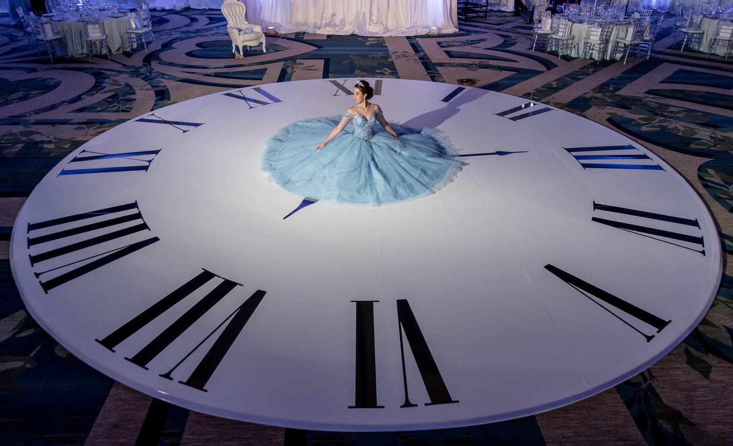 Quinceañera sits in blue ball gown on clock-shaped dance floor | PartySlate