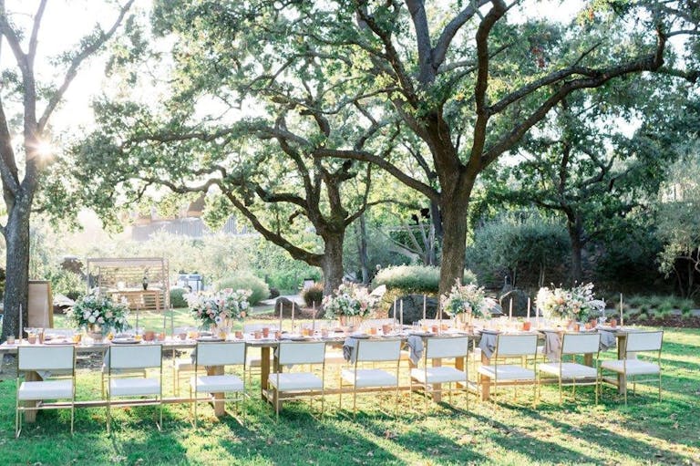 White table and chairs with vibrant floral centerpieces in Chandon winery’s garden wedding venue | PartySlate