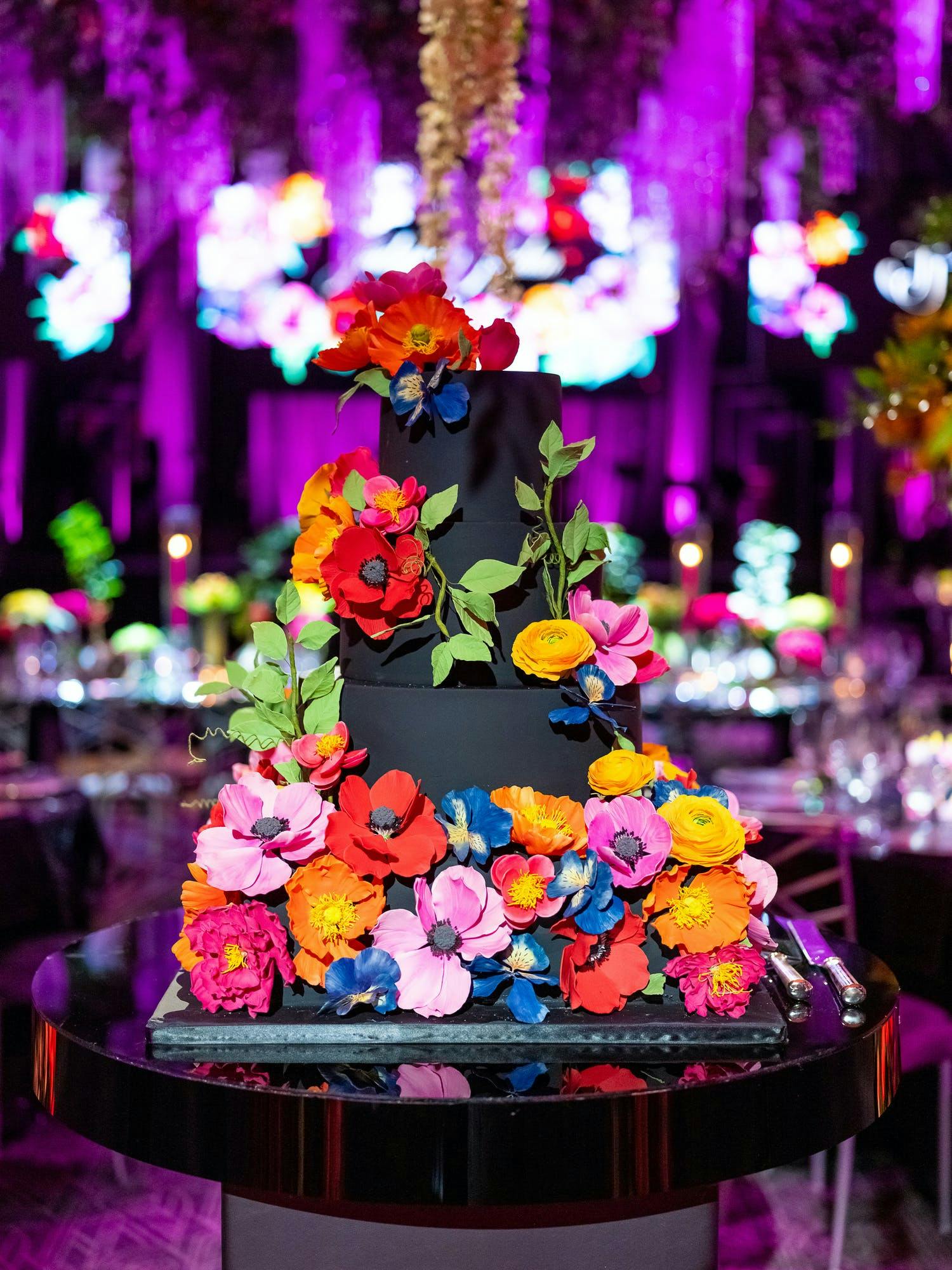 Black three-tiered cake covered in bright, colorful flowers | PartySlate | PartySlate