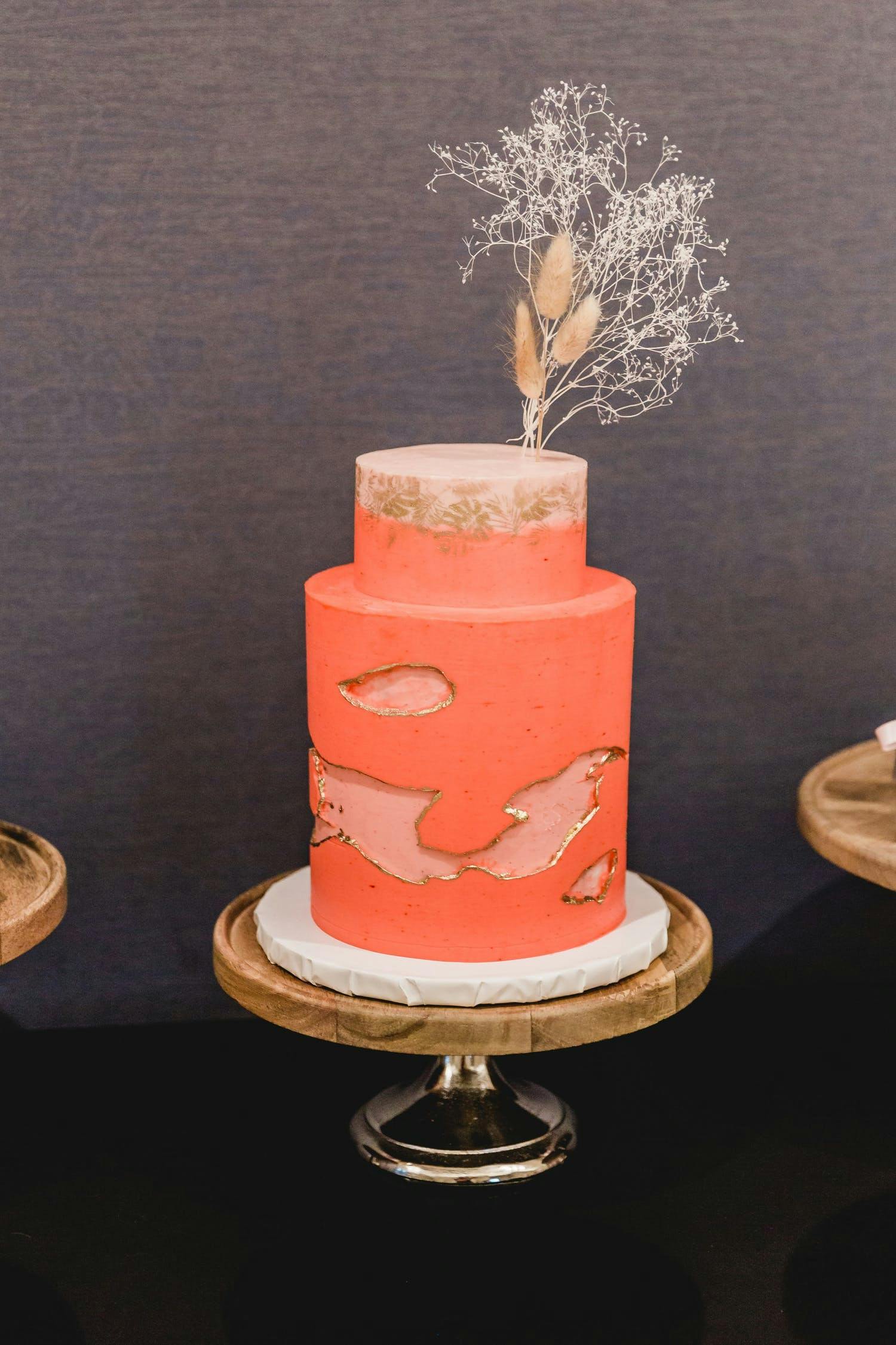 Two tier salmon-colored wedding cake with unique design | PartySlate