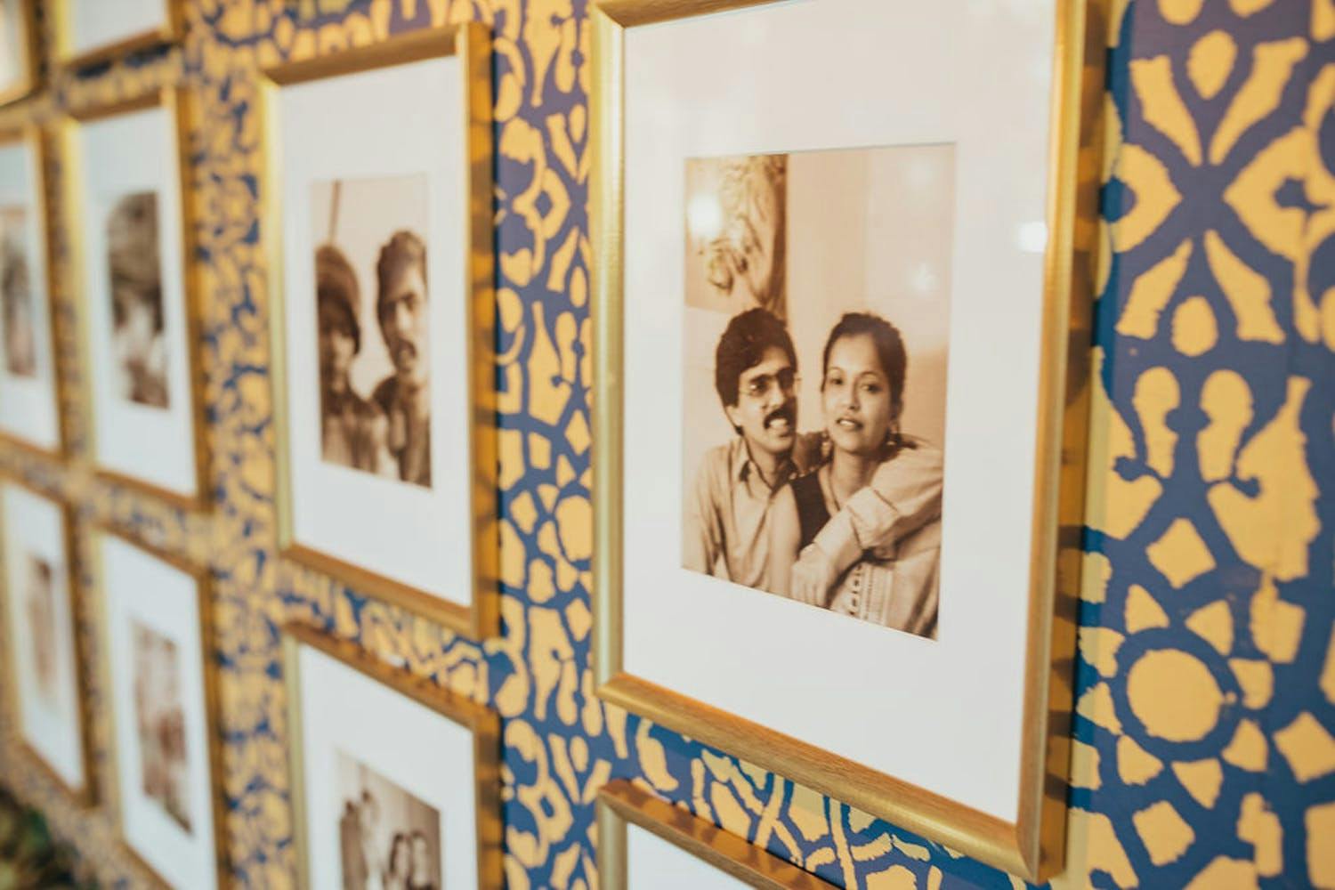 Wall of photos of couple at jewel-toned wedding anniversary party | PartySlate