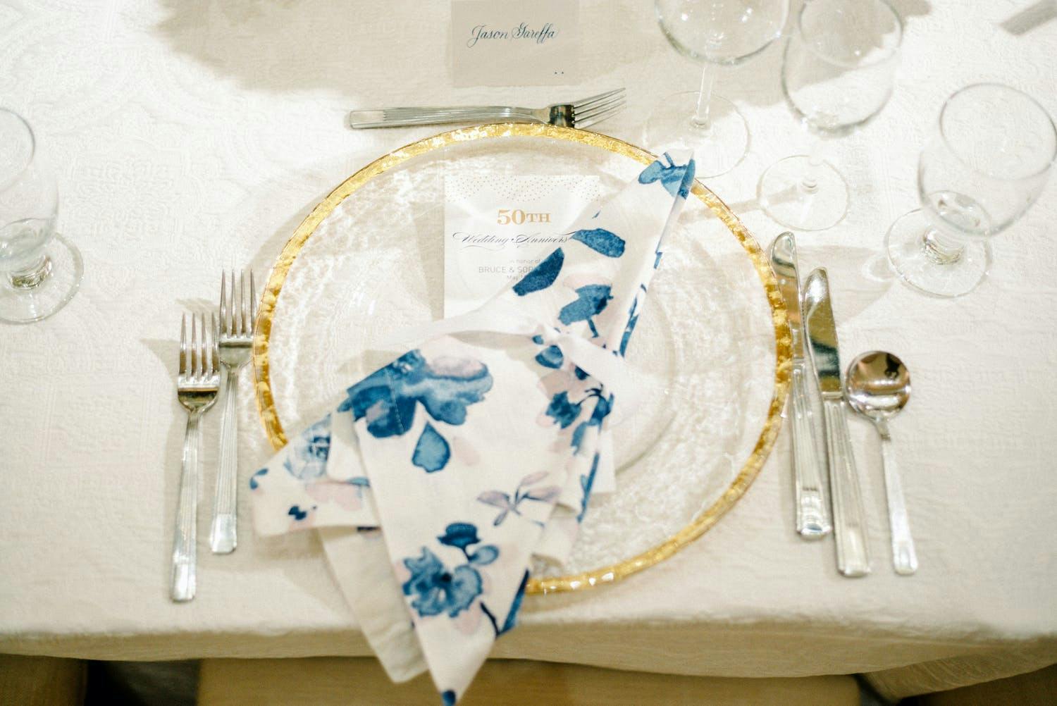 Elegant dinner plate with blue and white floral napkin at 50th-wedding anniversary | PartySlate