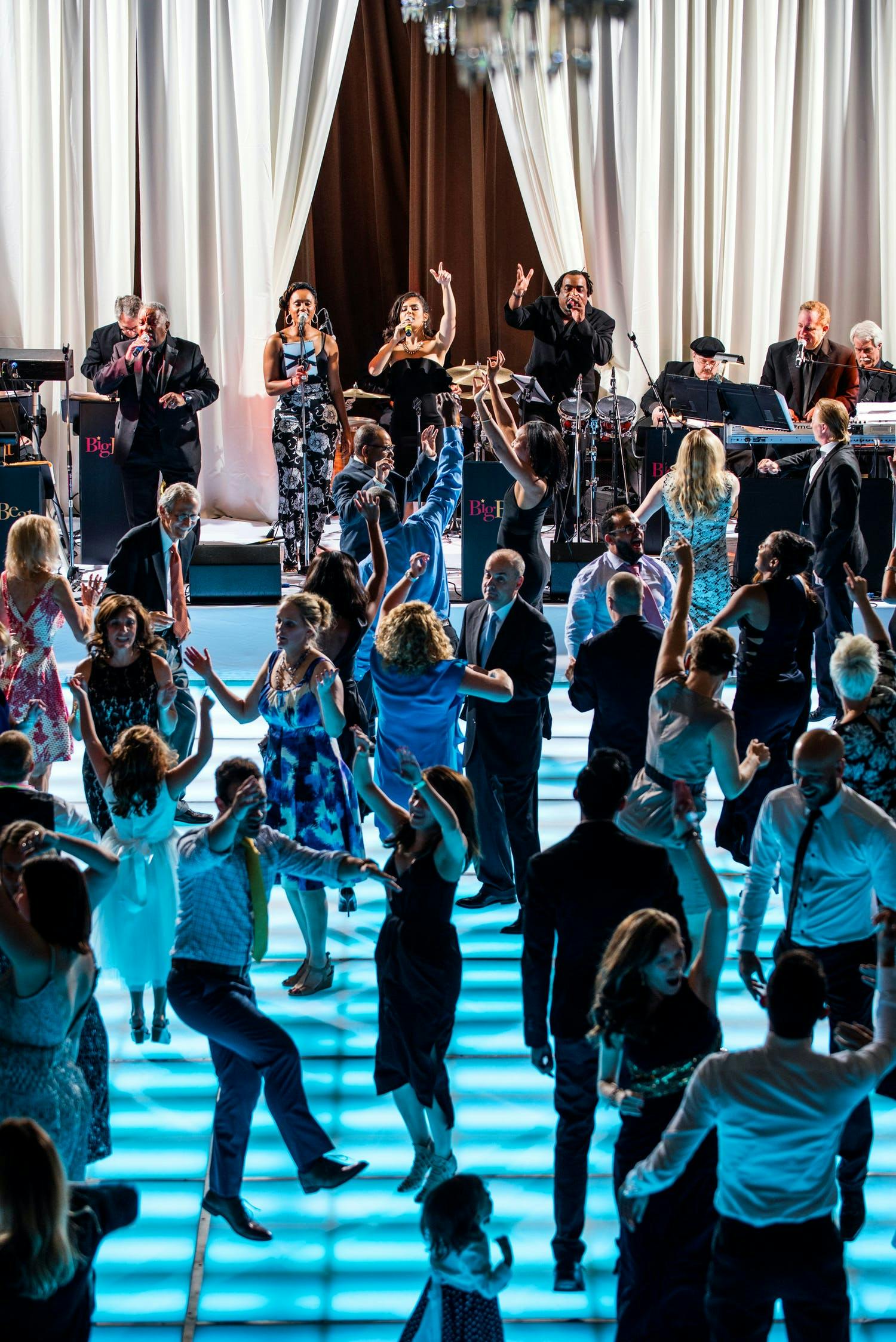 Guests dance on LED blue dance floor at wedding with performance by band Cagen Music LLC of Chicago, IL | PartySlate
