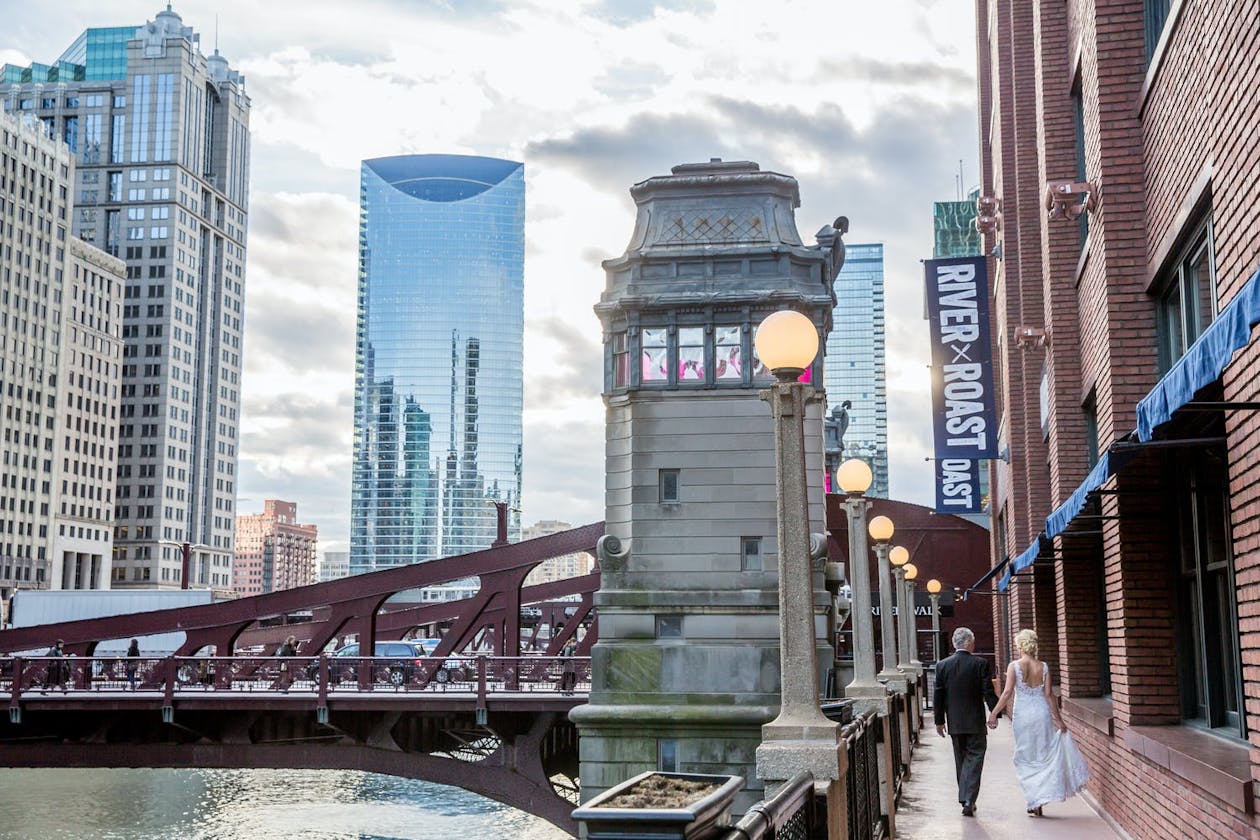 Bride and groom walk down Chicago Riverfront at River Roast Social House for their restaurant wedding Chicago | PartySlate