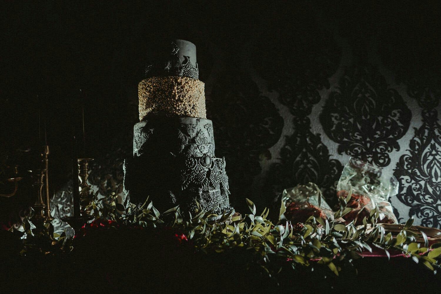 Moody black wedding cake with multiple textures and one tan tier | PartySlate