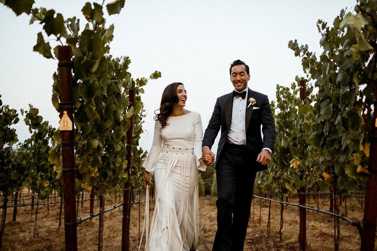 Bride and Groom walk through vineyards at Arista Winery in Healdsburg, CA | PartySlate