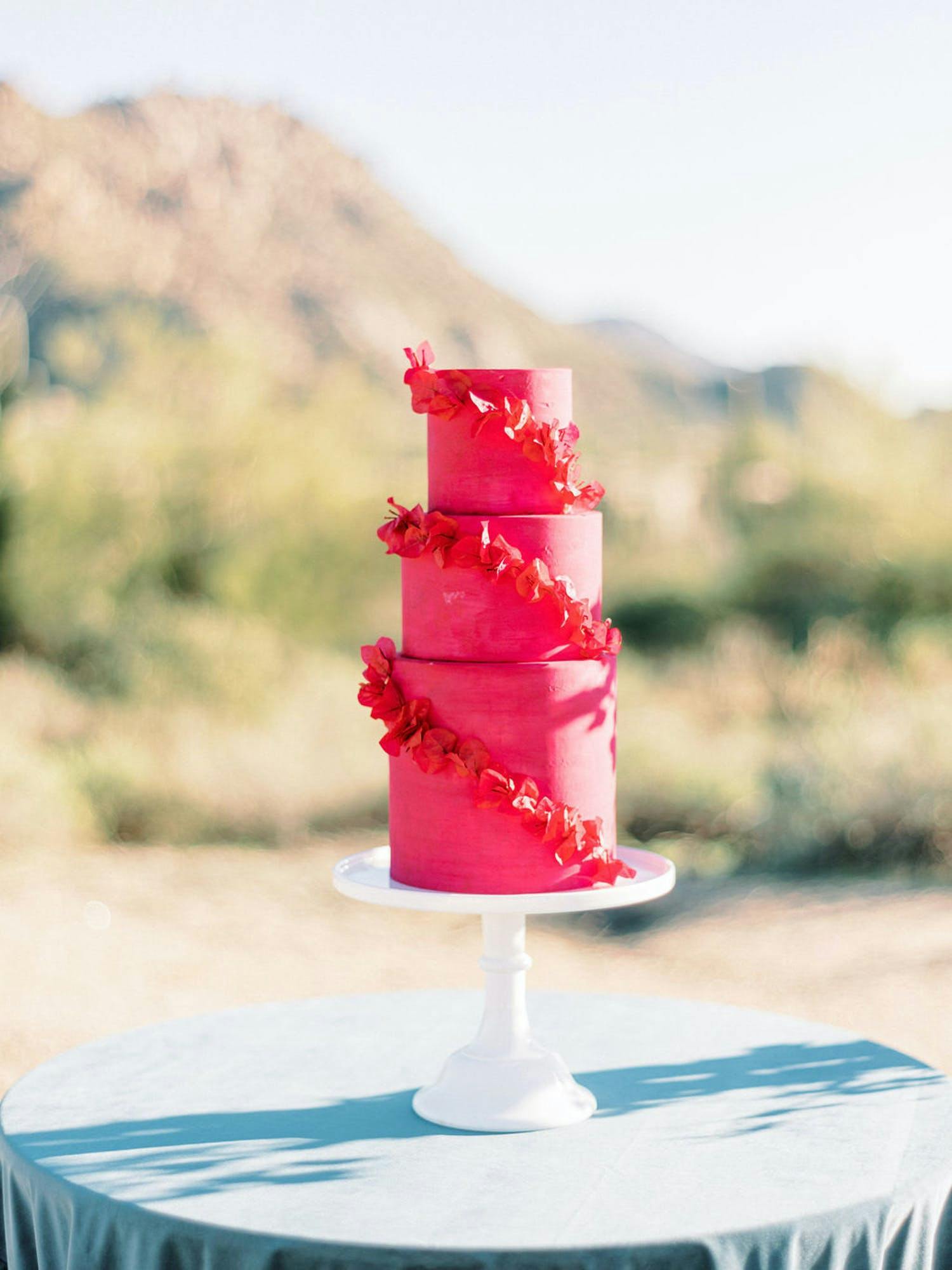 Three-Tiered Hot Pink Wedding Cake With Red Orchids Wrapped Around It | PartySlate
