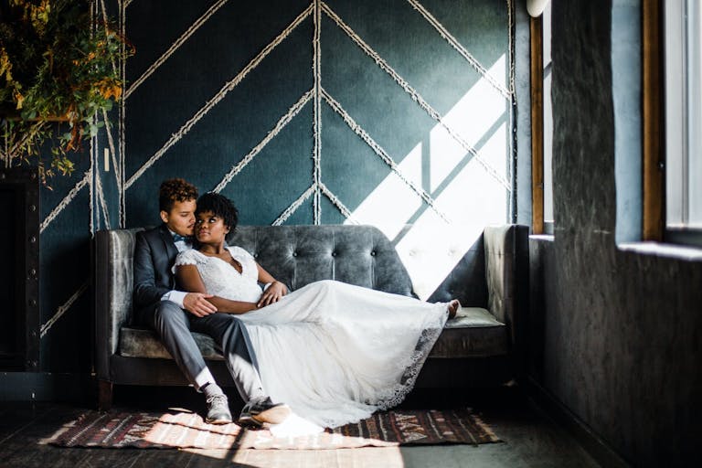 Bride and groom rest on sofa against chevron-denim wall backdrop at The Dawson in Chicago, IL | PartySlate