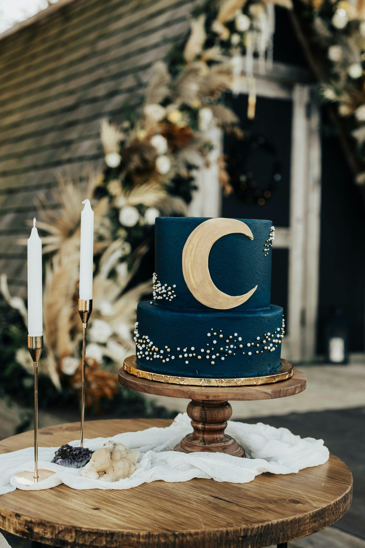 Two-tier navy blue wedding cake with crescent moon design on top tier | PartySlate