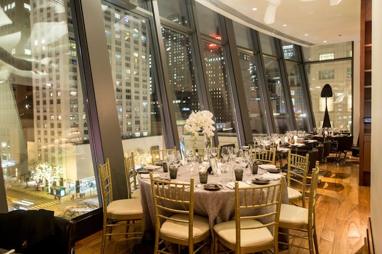 Wedding reception at NoMI Kitchen with floor-to-ceiling cantilevered windows that show off both downtown Chicago and Lake Michigan | PartySlate