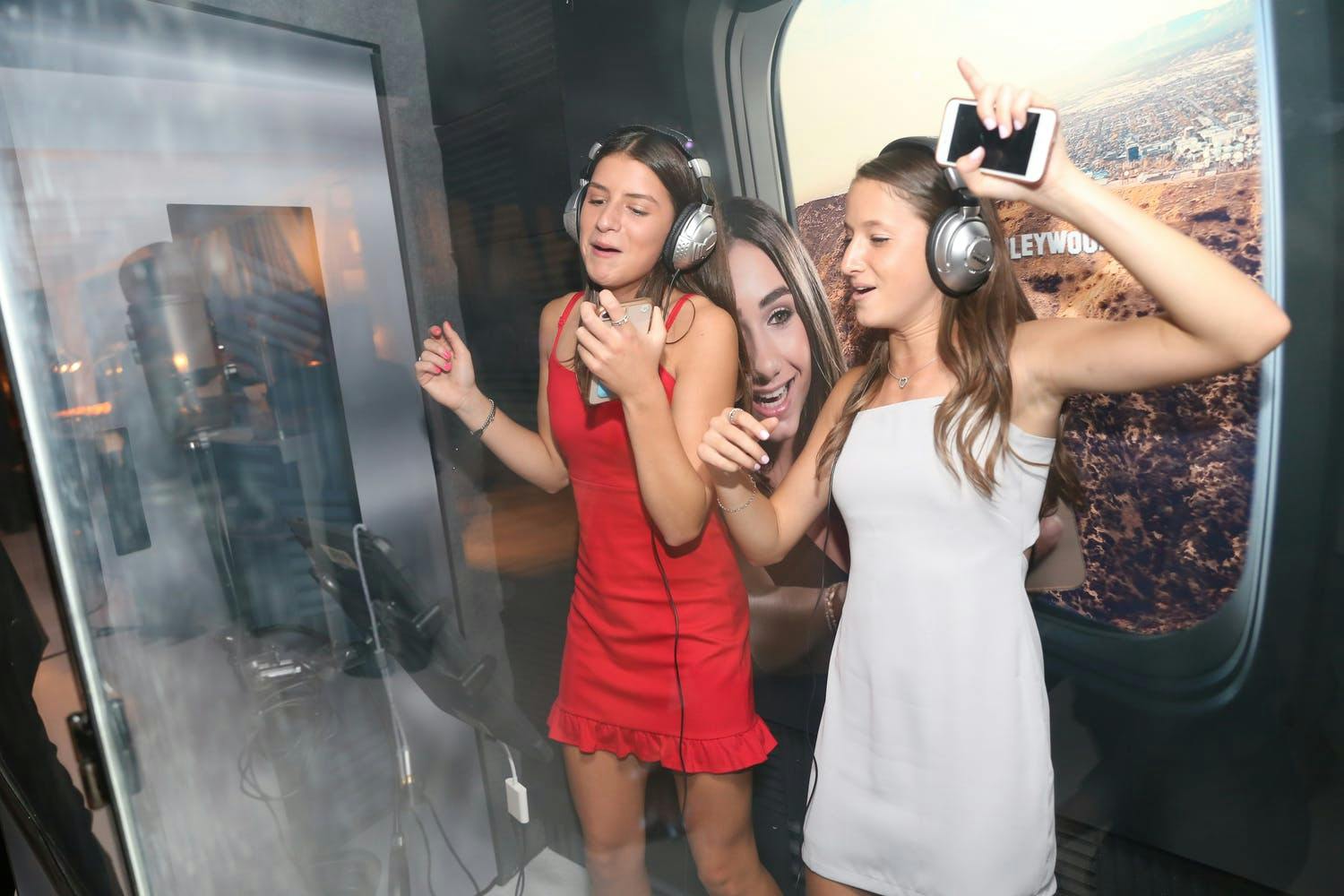 Two girls sing in recording studio booth for a corporate event activity | PartySlate