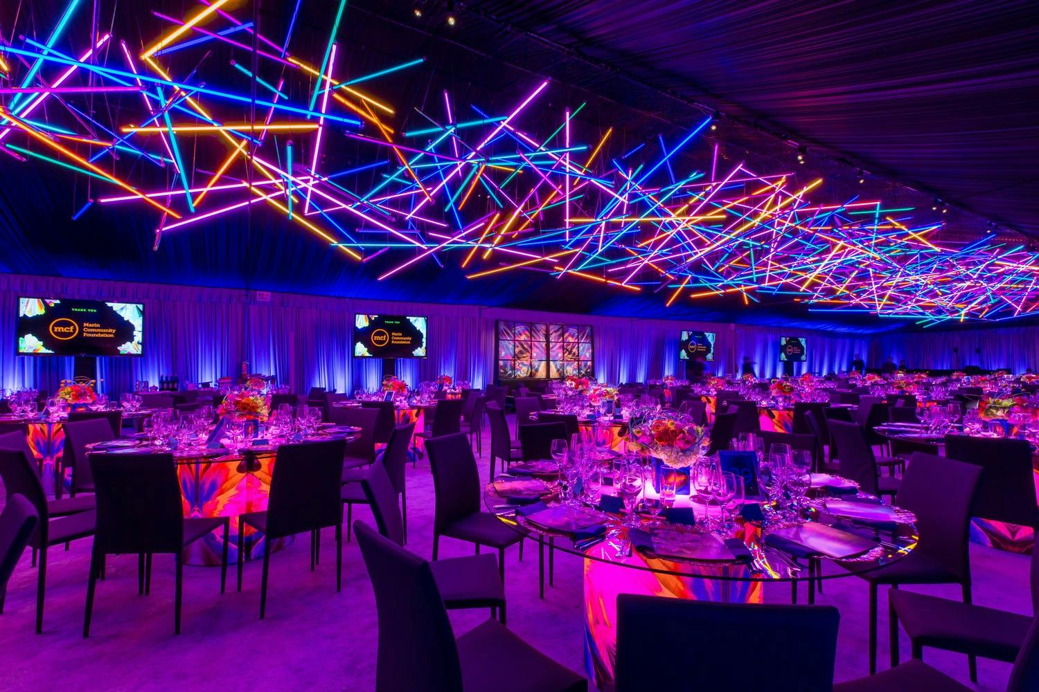 Geometric blue, orange, and pink neon lights ceiling installation at electric gala | PartySlate