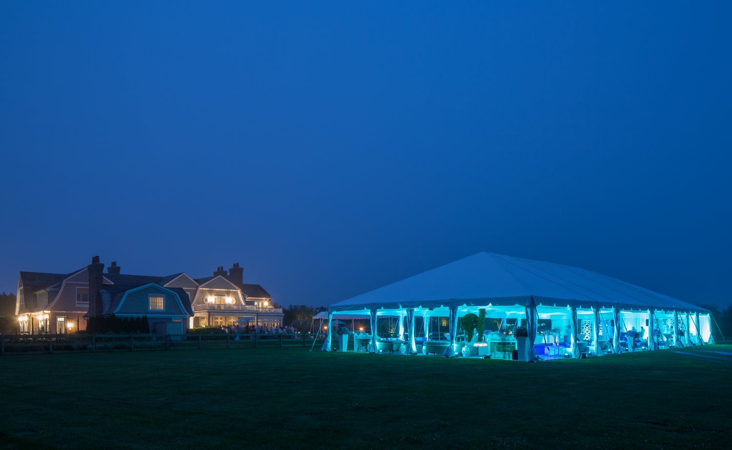 Tented 30th-wedding anniversary with blue uplighting at night | PartySlate