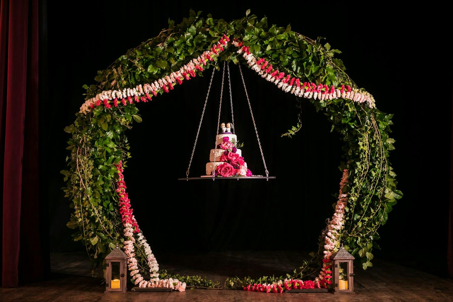 Three-tier pink floral wedding cake hanging from a swing | PartySlate