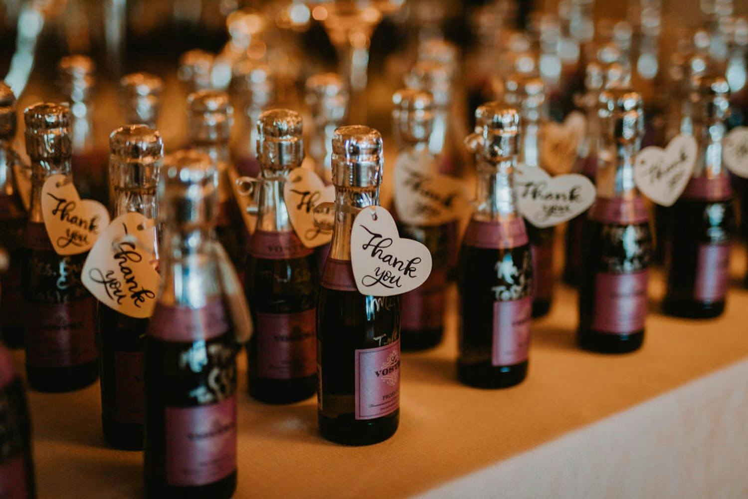 Mini Champagne bottles with purple labels for wedding anniversary party | PartySlate