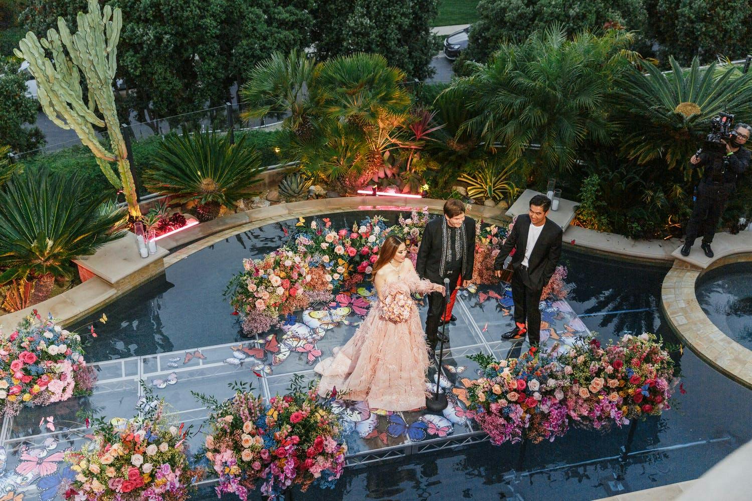 Anniversary Party Ideas: Couple renews vows on floating wedding aisle lined with bright and colorful flowers | PartySlate