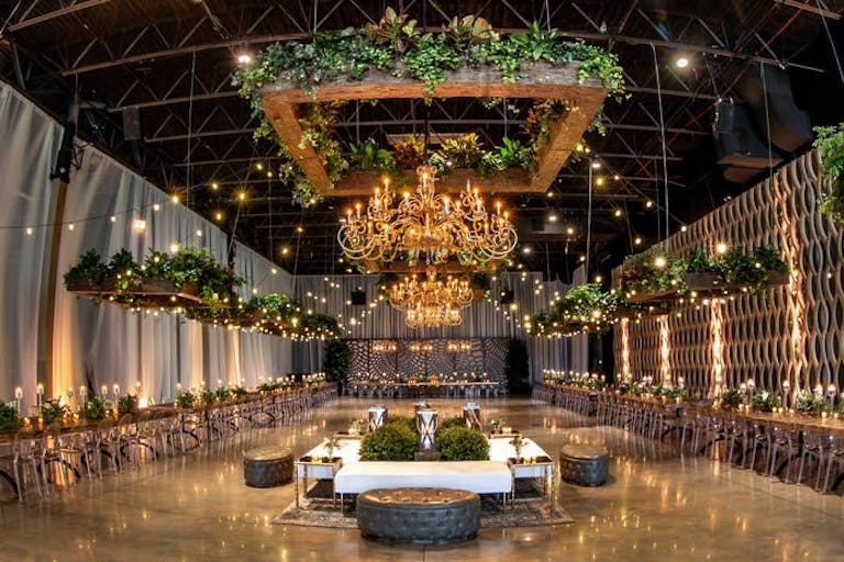 industrial wedding venue with white drapery, greenery, and chandeliers at Geraghty in Chicago | PartySlate