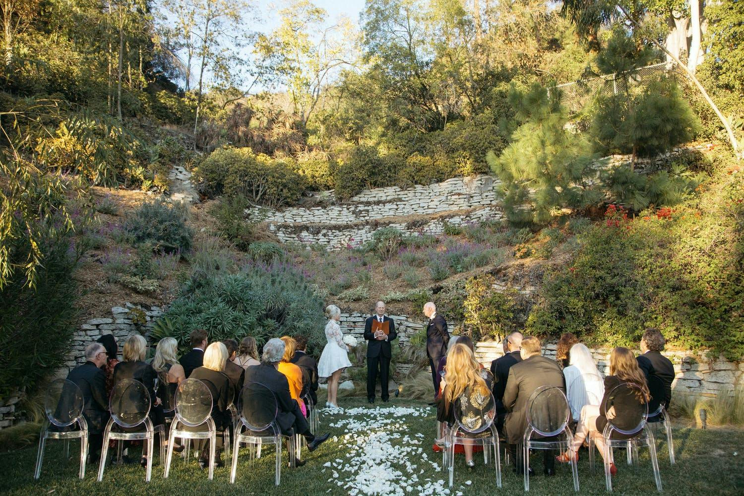 Elegant backyard wedding ceremony with white petal aisle | PartySlate