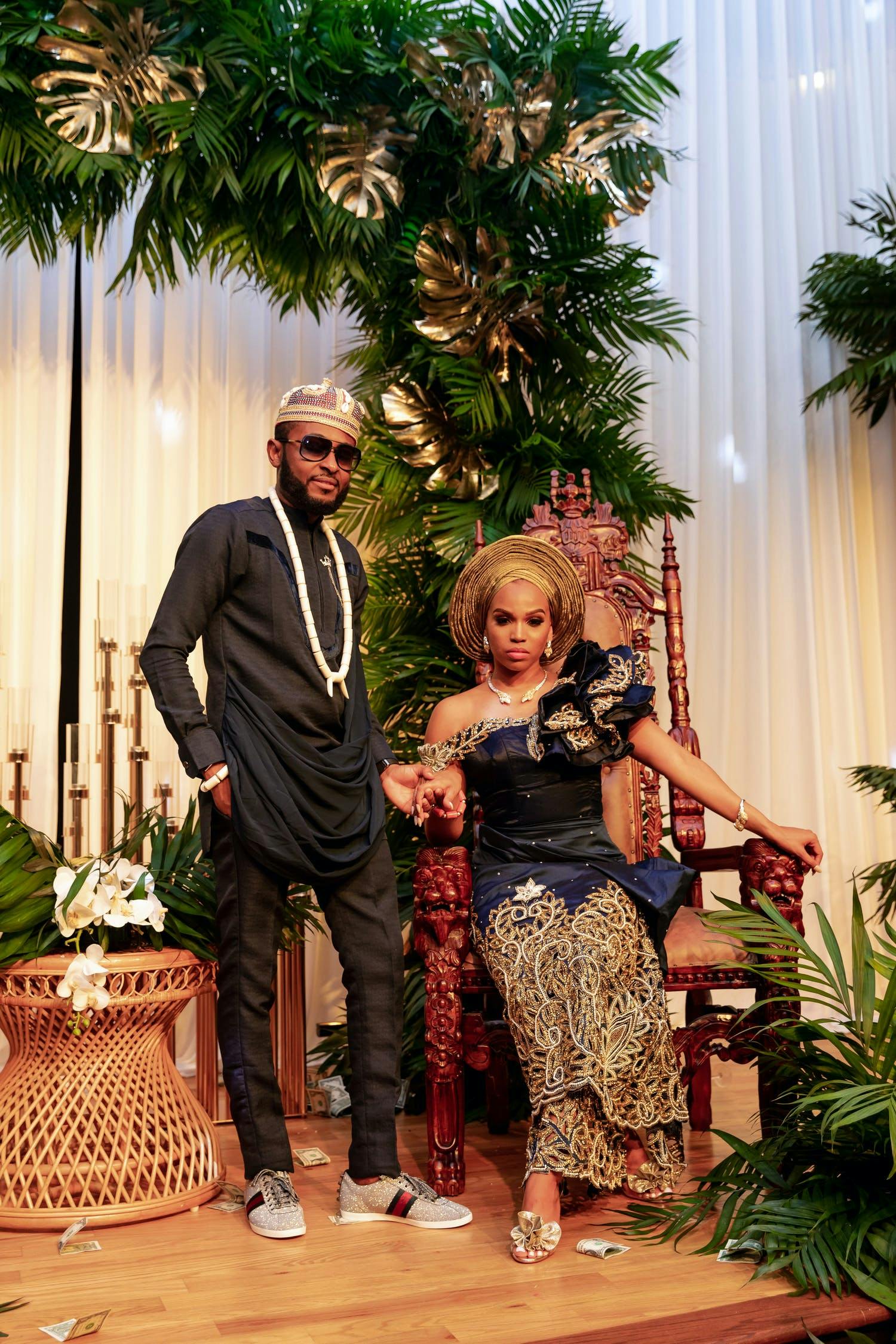 Bride and Groom pose in front of tropical foliage at Nigerian Wedding | PartySlate