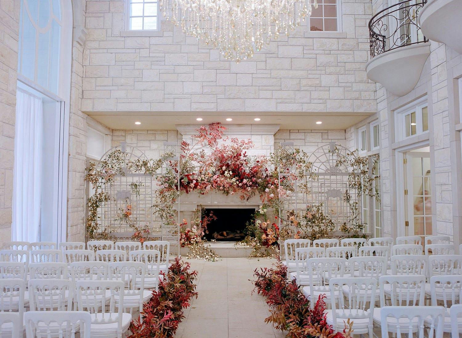 Indoor fall wedding with terracotta flower décor and white brick backdrop with fireplace | PartySlate