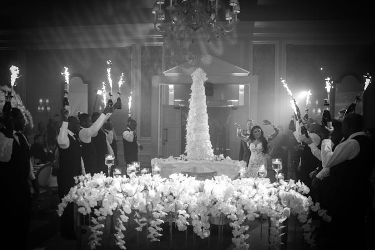 Bride Dancing with Champagne Bottle Sparklers at Dazzling White and Gold Wedding | PartySlate