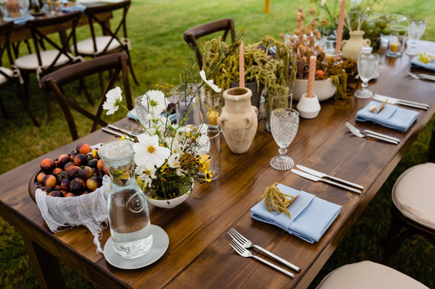 Walnut farm table filled with rustic pottery, green amaranth, and fall fruits for fall wedding | PartySlate