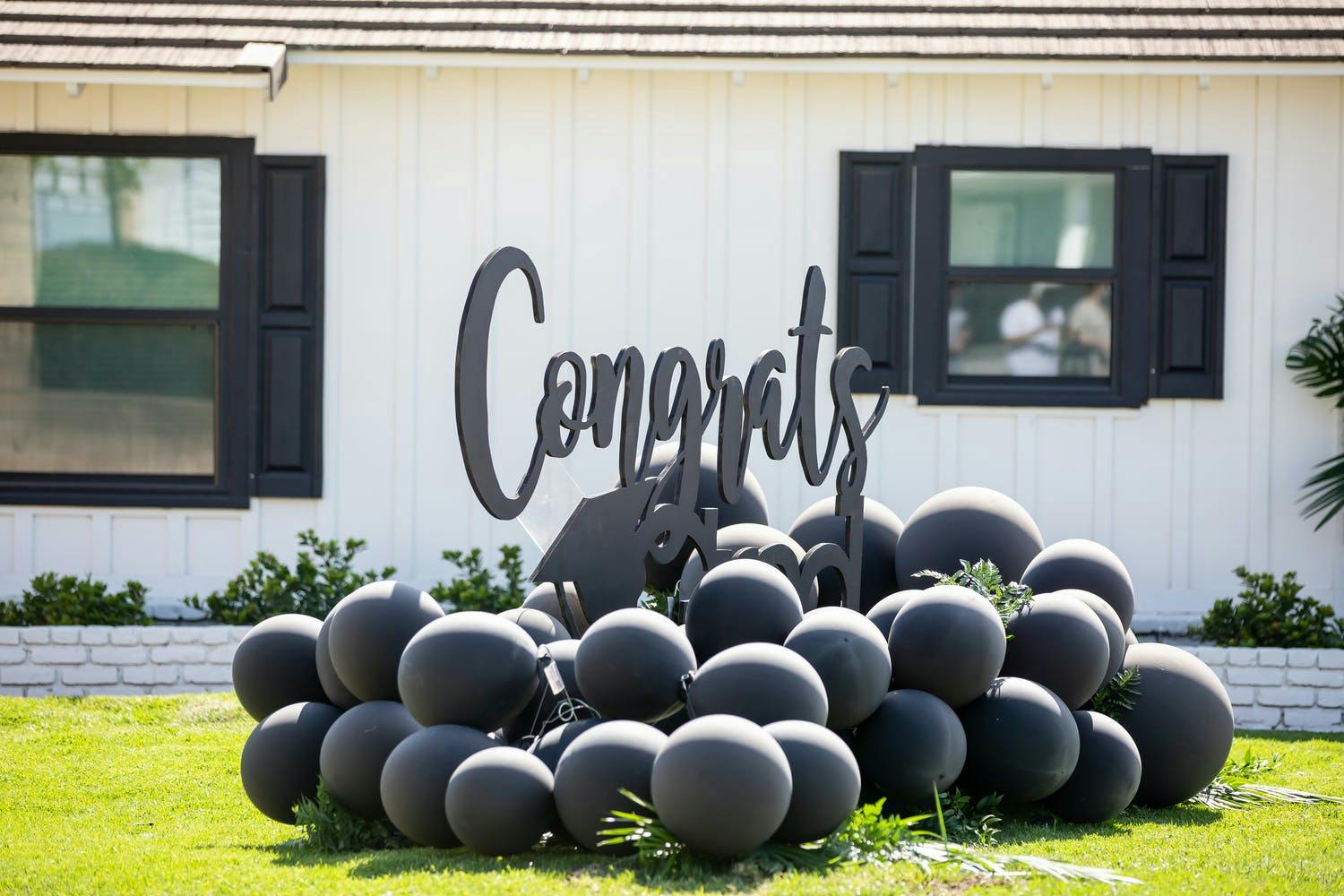 Cluster of black matte balloons with cursive black signage that reads 