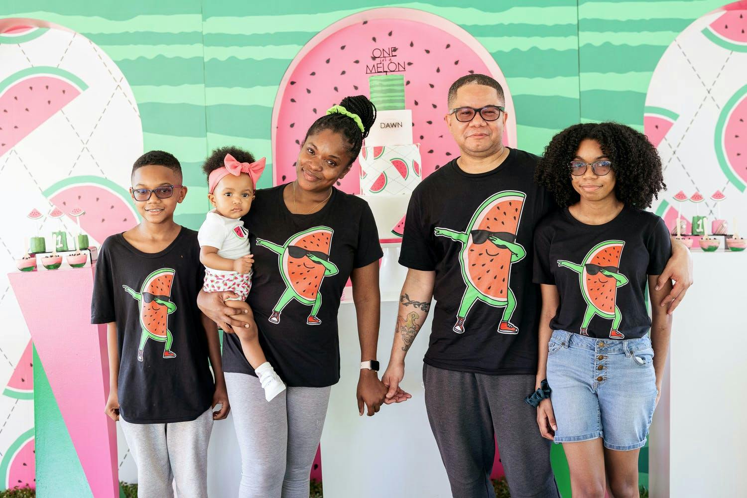 Family of five poses in black and pink watermelon t-shirts at watermelon-themed birthday party | PartySlate