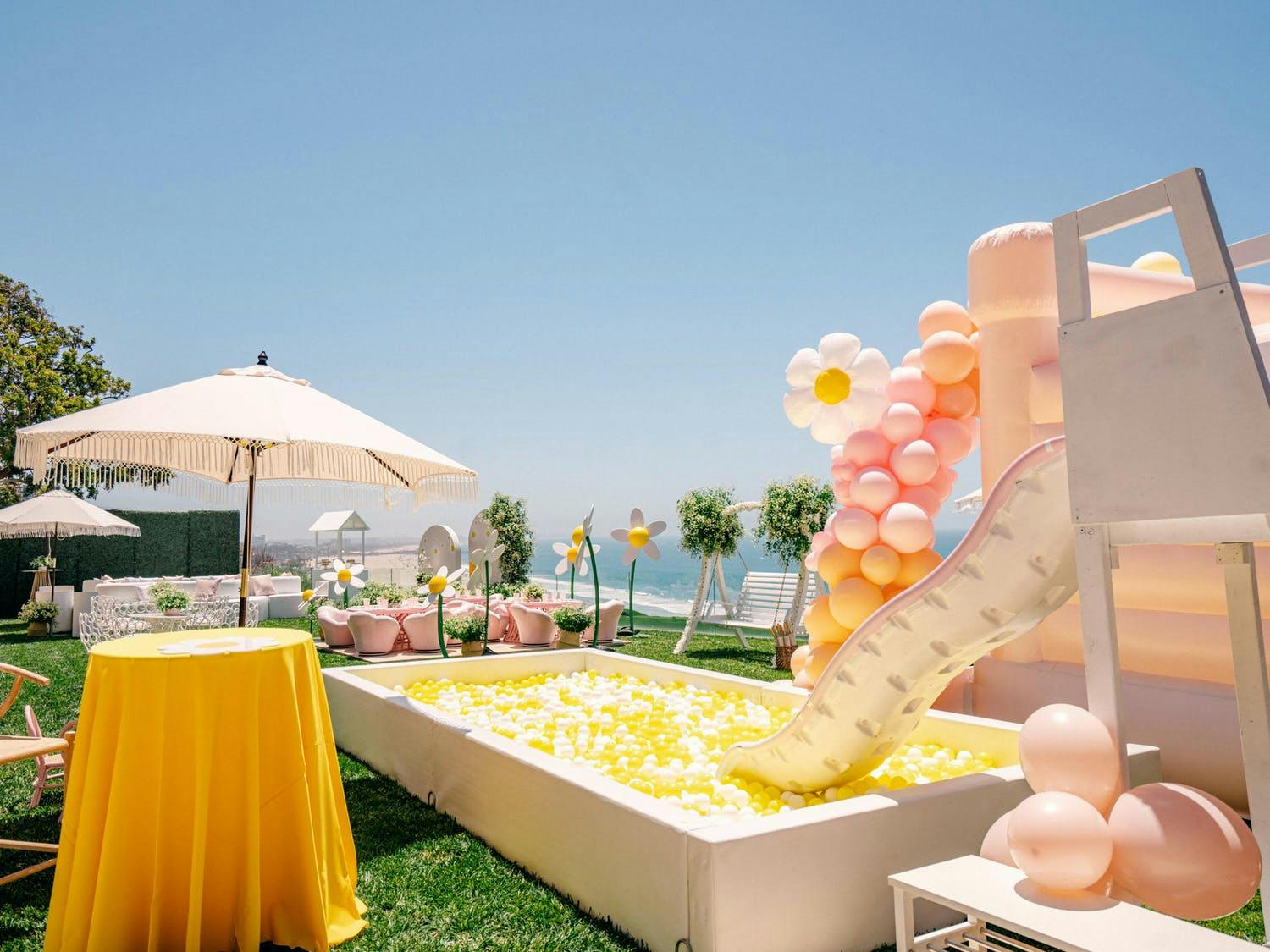 Daisy-themed outdoor kid's birthday party with a slide and yellow ball pit | PartySlate