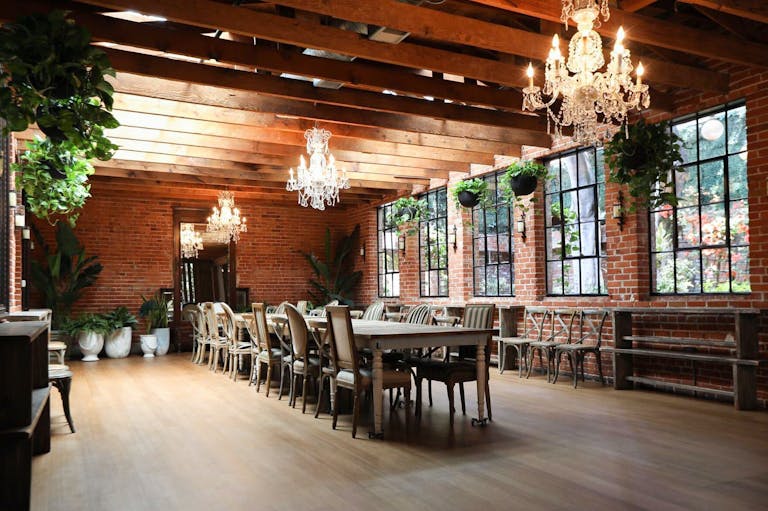 Salle at Carondelet House with exposed brick, greenery, and king's table for holiday party | Partyslate