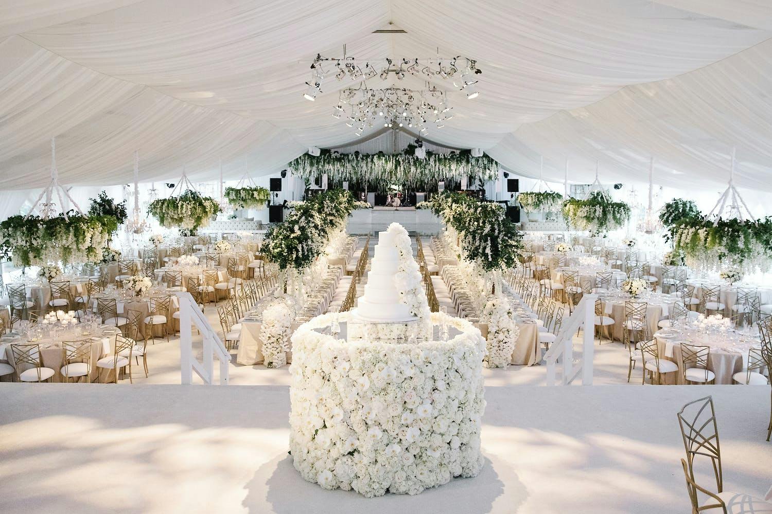 White tented wedding with white rose covered cake stand | PartySlate