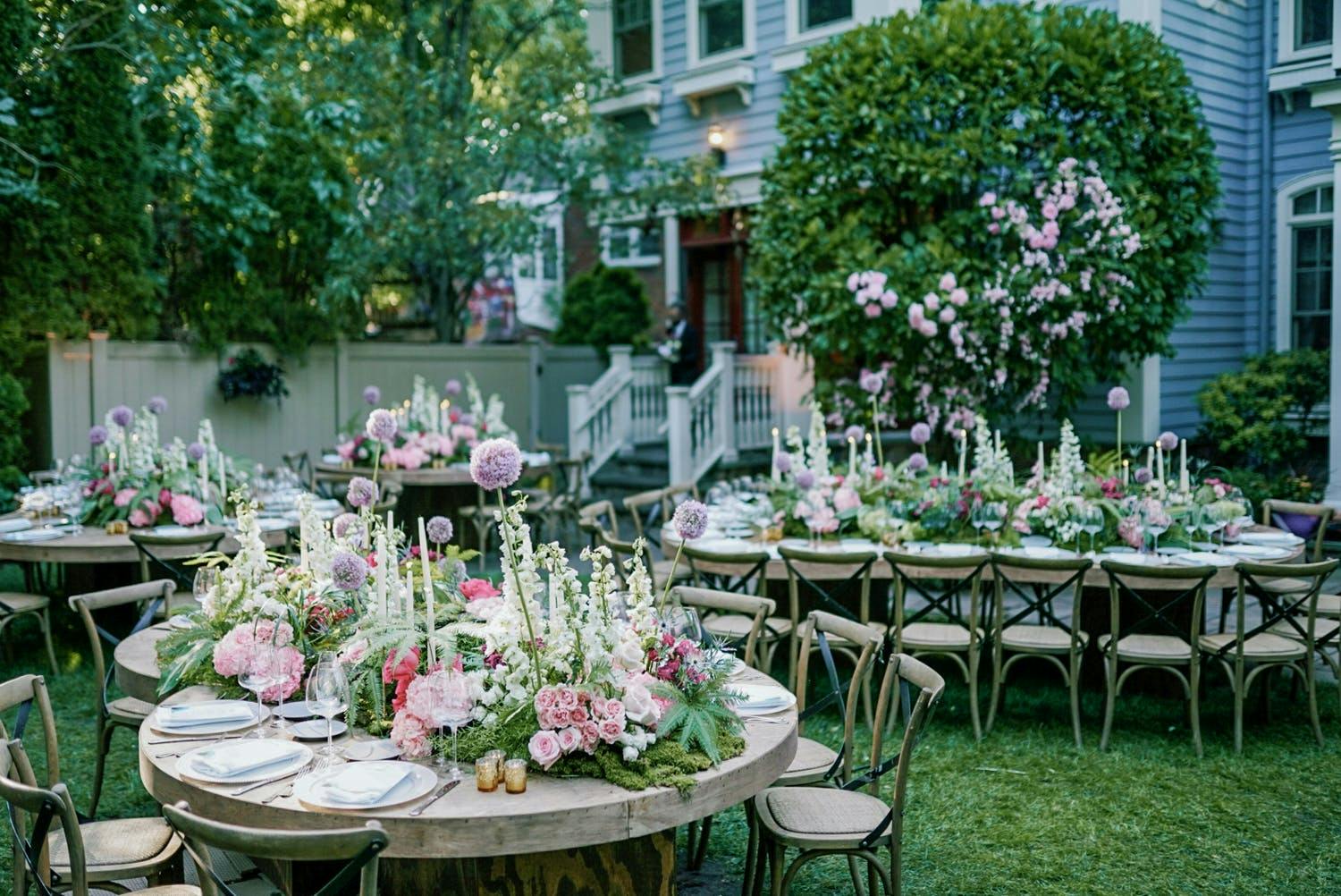 Backyard wedding with tablescapes of lavish greenery, white spiky florals, and purple allium | PartySlate