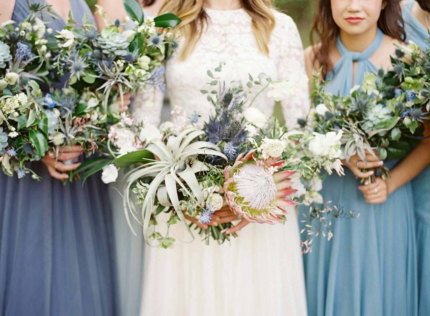 Bride and bridesmaids hold wildflower bouquet in spring wedding colors | PartySlate