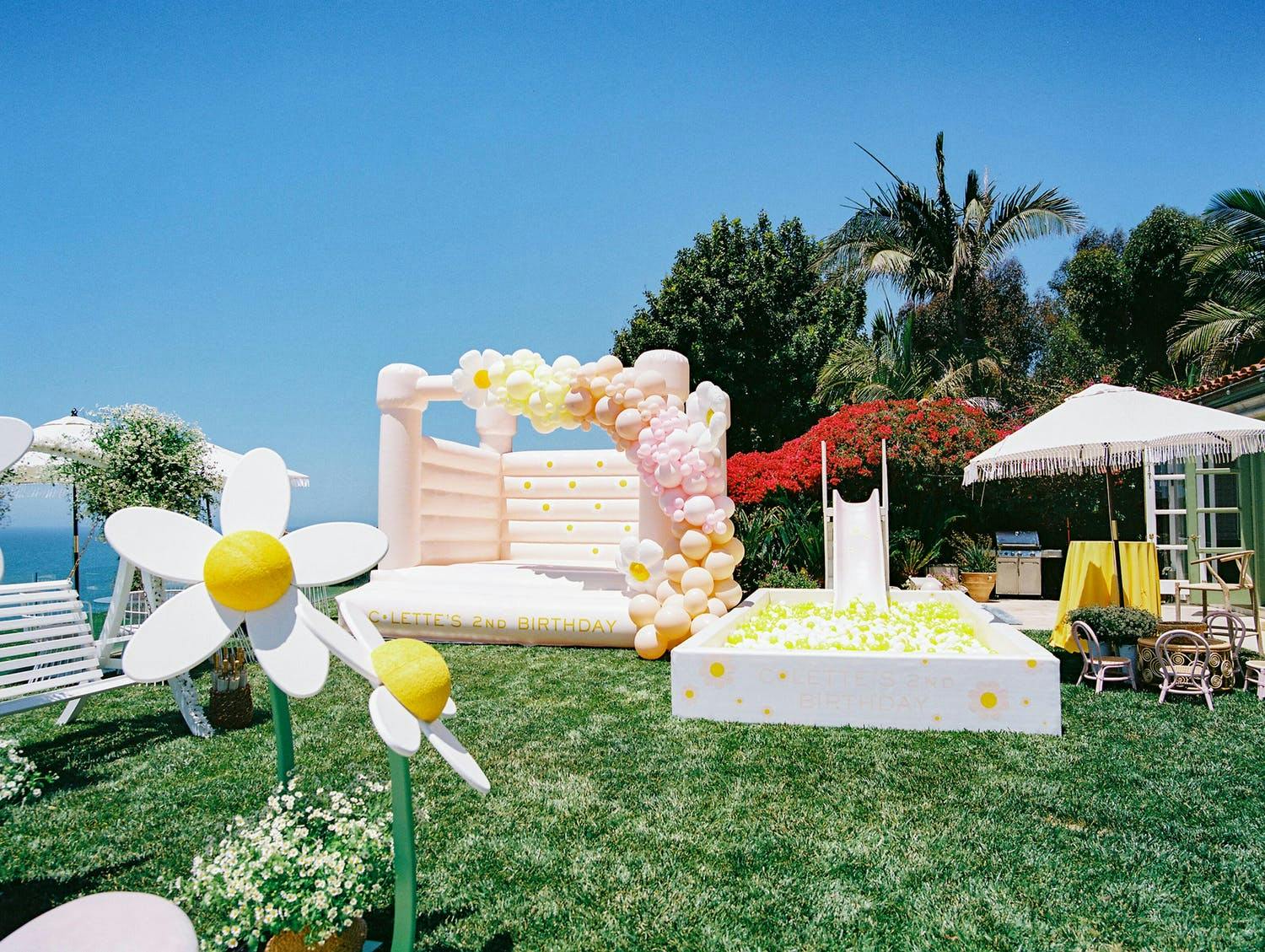 Outdoor daisy-themed kid's birthday party with ball pit and bouncy house | PartySlate