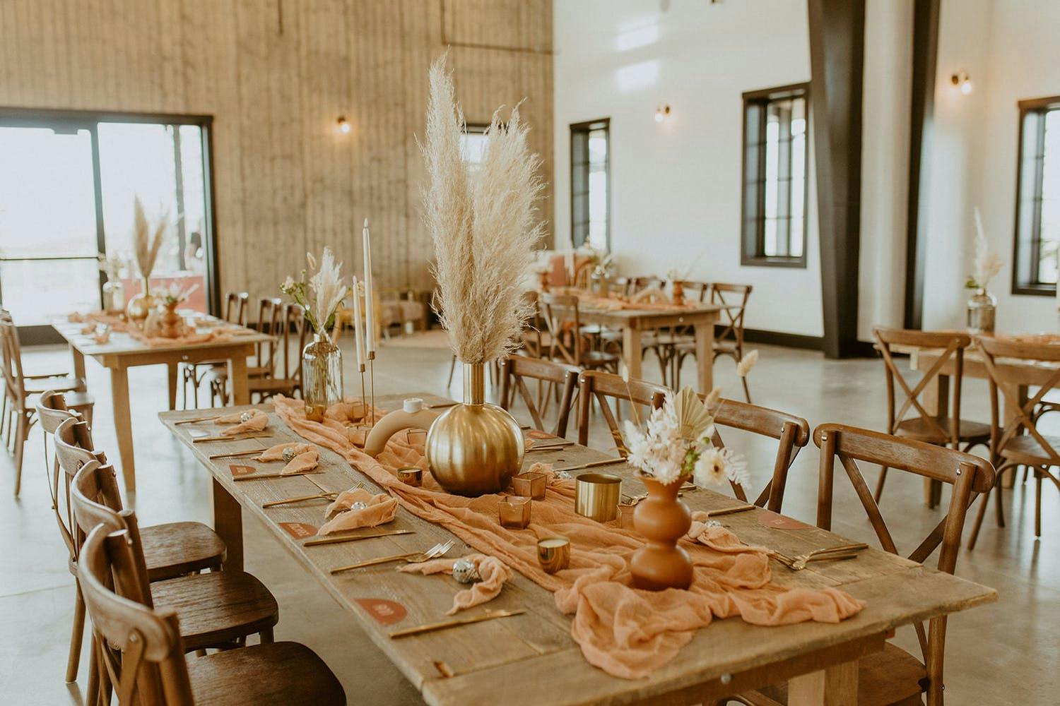 Modern fall wedding table with pottery-colored table runner and pampas grass in gold pumpkin vase | PartySlate