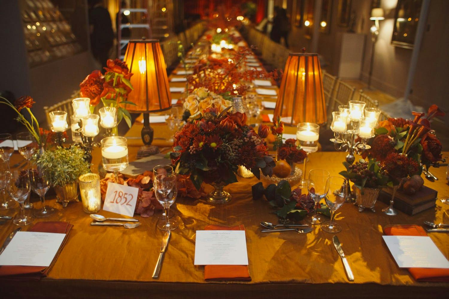 Fall wedding table with amber lamps, vintage books, and gold and flowers | PartySlate