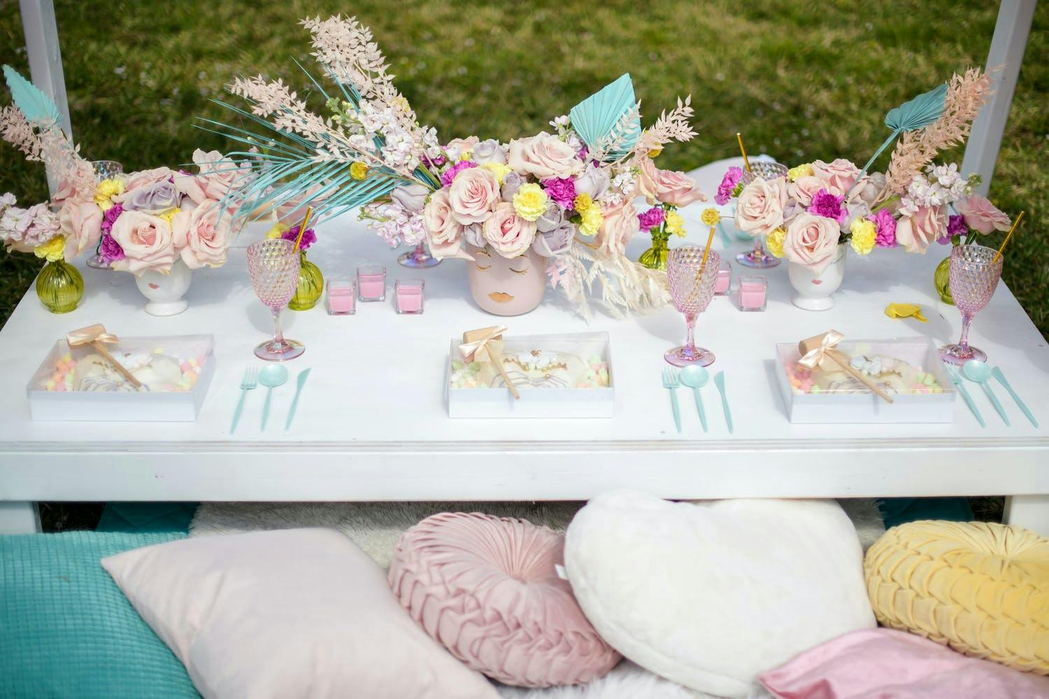 Outdoor kid's birthday party with low tables, pillow seats, and pastel-dyed floral centerpieces | PartySlate
