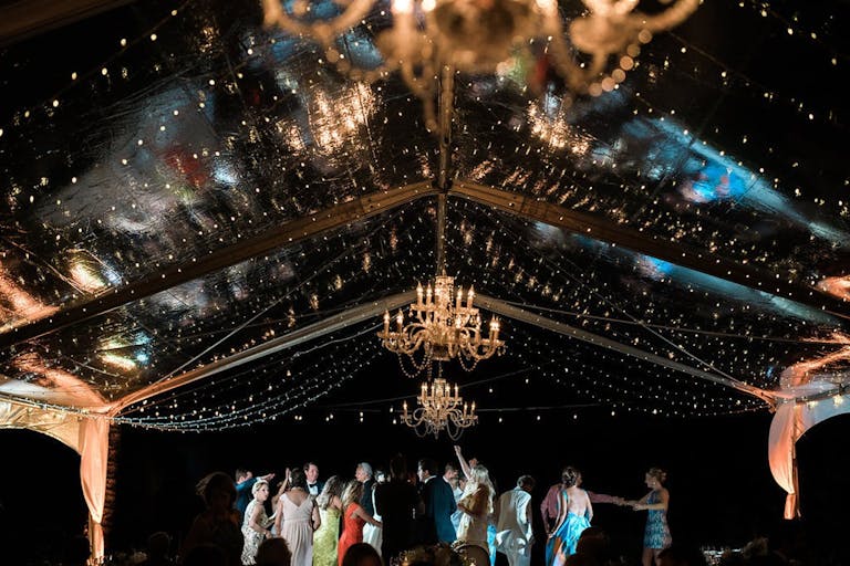 Wedding Reception with teh Night Sky and Stars Lighting Up The Venue Under a Tent With String Lights | PartySlate