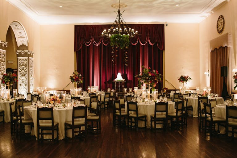 Full First Floor at The Ebell of Los Angeles with burgundy drapery and greenery on rustic chandelier | PartySlate